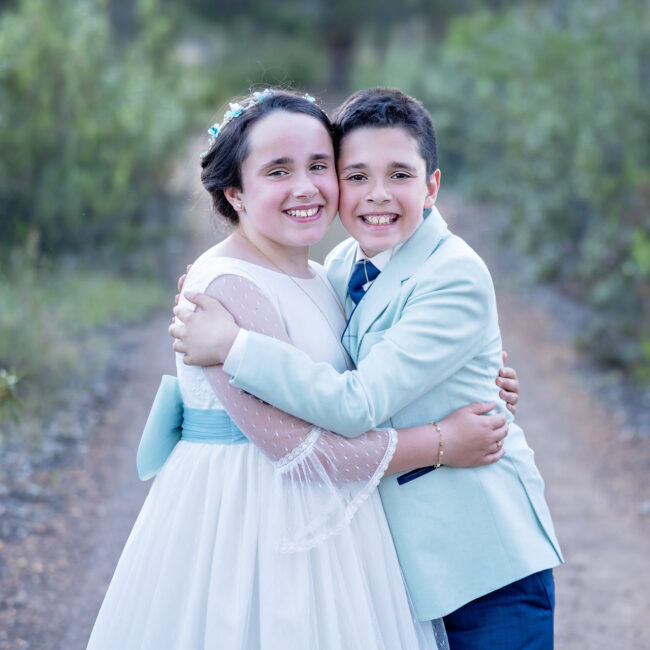 Mariana y David abrazados en los caminos de tierra rojiza de La Zarza en su sesión de comunión.