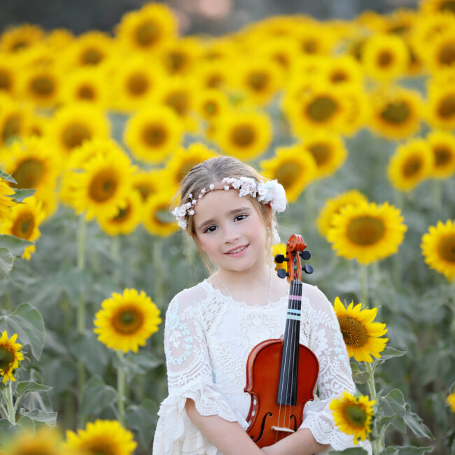 Retrato de comunión de Montemayor con un violín entre girasoles