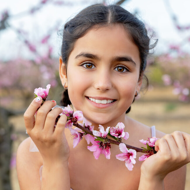Retrato infantil de Cecilia sonriente sosteniendo una rama con flores rosas