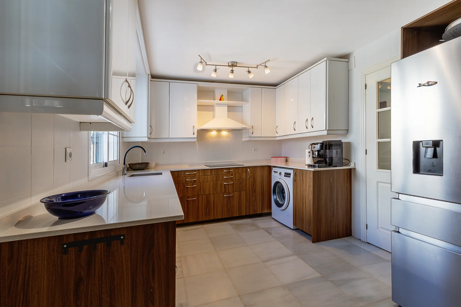 Kitchen with white and wooden cabinets in a villa in Nuevo Portil, Huelva
